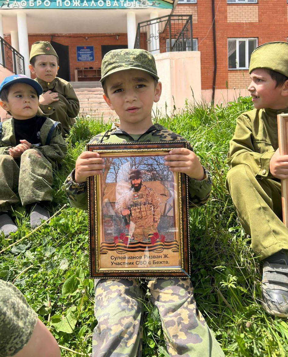 Дети с фотографиями  отцов участников СВО на Украине.