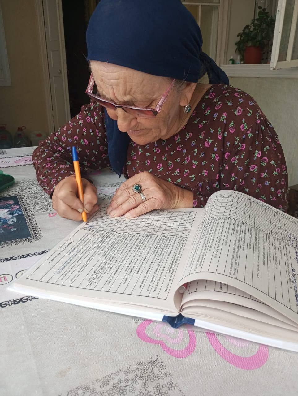 Подопечная социального работника 1 отд. СО на дому Напилуновой Нуржавгар ставит отметку в журнале об оказании ей социальных услуг.