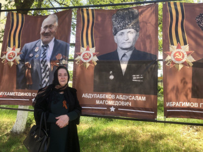 Абутова Хадижат Абдусаламовна у баннера своего отца