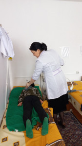 Медицинская сестра Салихова Гульжаминат Р. проводит физ. процедуры подопечному Курбанову И. Д., электронейростимуляцию.